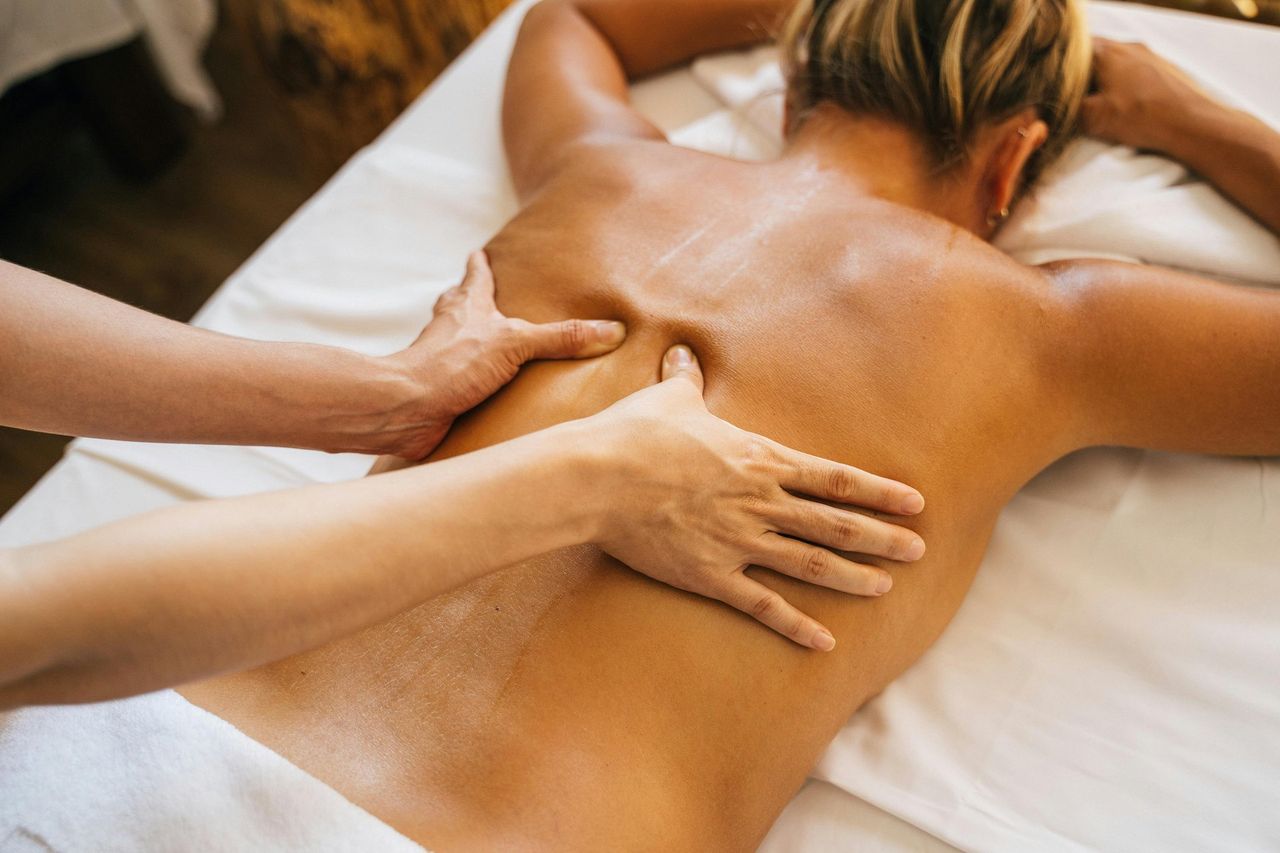 Wohlfühlmassage: Eine Frau liegt auf dem Bauch und bekommt eine entspannende Rückenmassage.